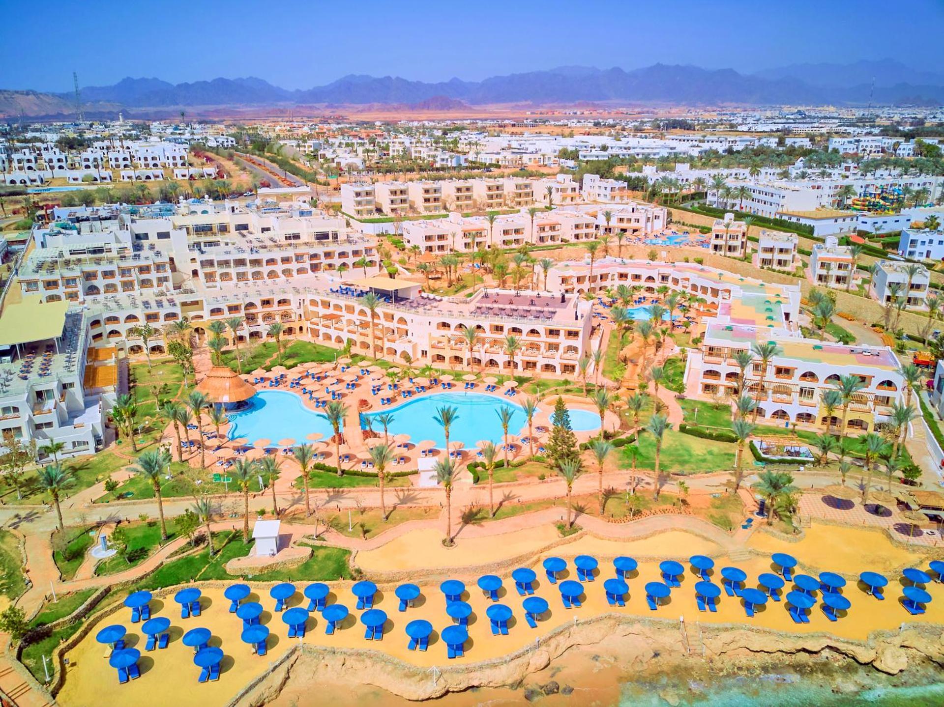 Pickalbatros Royal Grand Sharm - Adults Friendly 16 Years Plus Sharm El Sheikk Exterior foto The photo shows a large resort complex set in a scenic location, likely near a beach. The layout features multiple buildings with a Mediterranean style of architecture, surrounded by lush greenery and palm trees. Central to the resort is a swimming p
