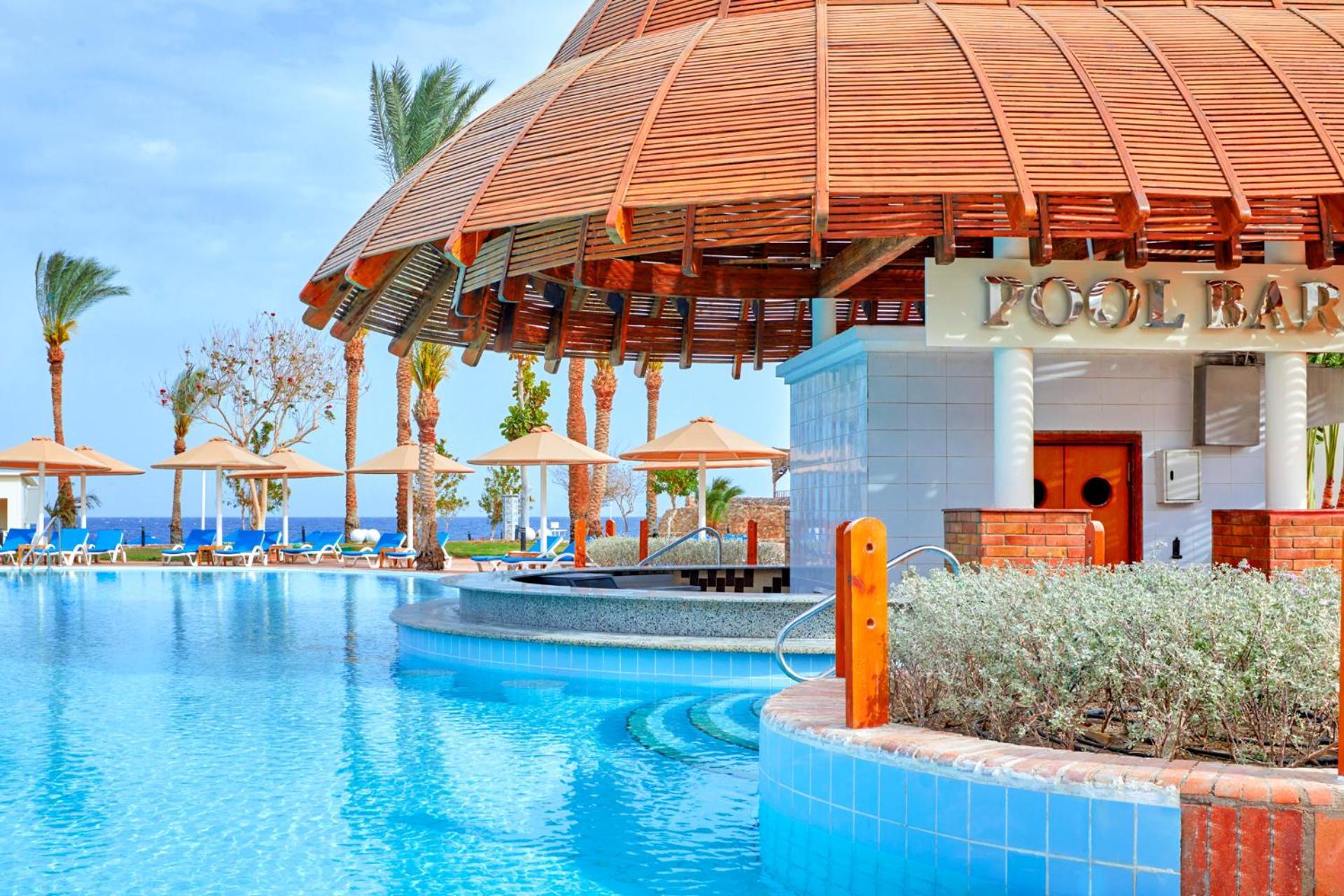 Pickalbatros Royal Grand Sharm - Adults Friendly 16 Years Plus Sharm El Sheikk Exterior foto The photo depicts a picturesque pool area at a resort. In the foreground, there is a clear and inviting swimming pool with curved edges, surrounded by a light blue tile border. To the side, a pool bar is visible with a wooden roof and stylish archite